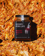 岩の背景に置かれた Honey for Life のデザート・マリー蜂蜜の瓶