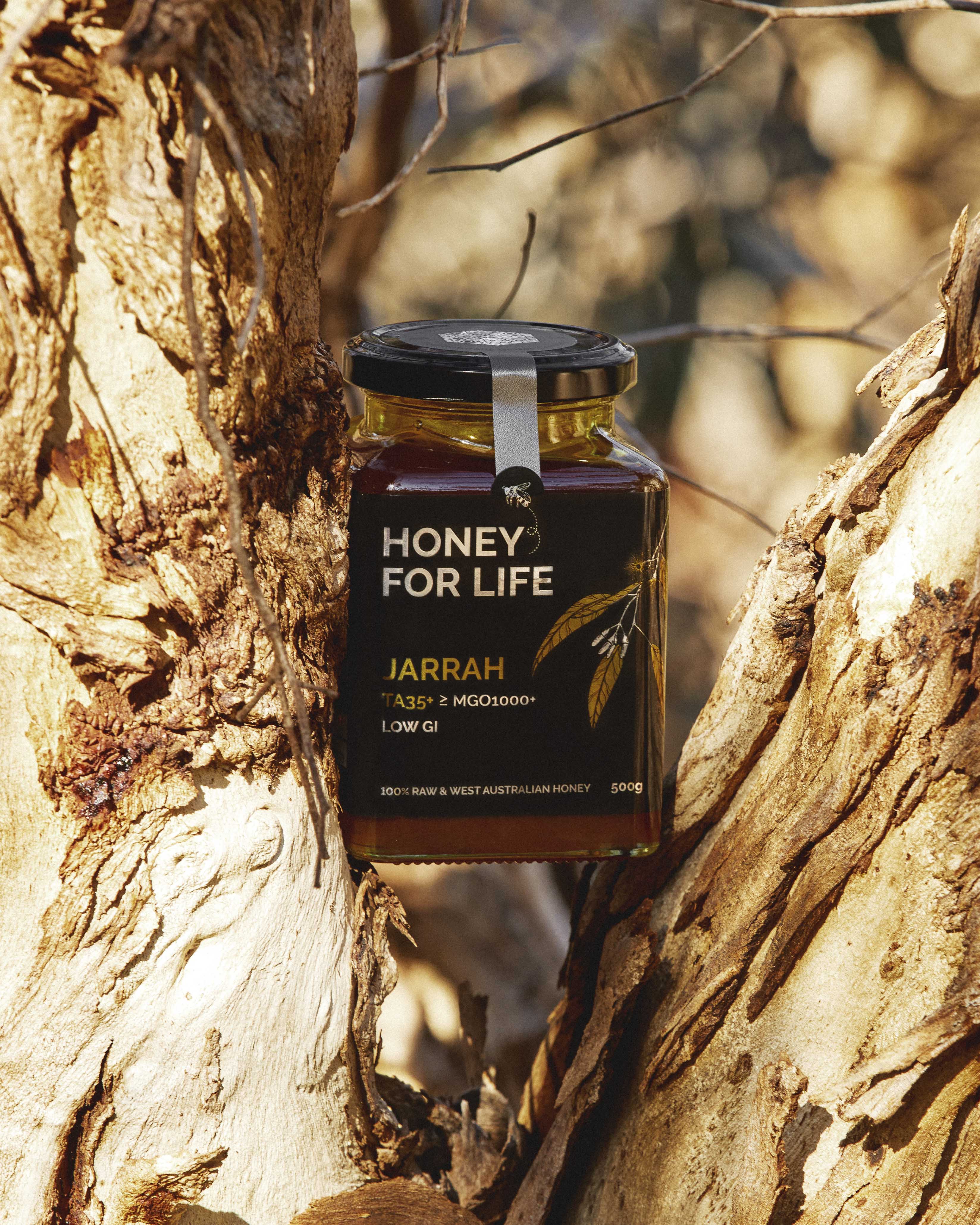 木の幹を背景にした「Honey for Life」のジャラ蜂蜜の瓶