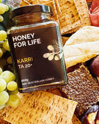 さまざまな料理が並ぶテーブルに置かれた ACTIVE KARRI HONEY TA20+ の瓶で、蜂蜜の試食の場面を示している