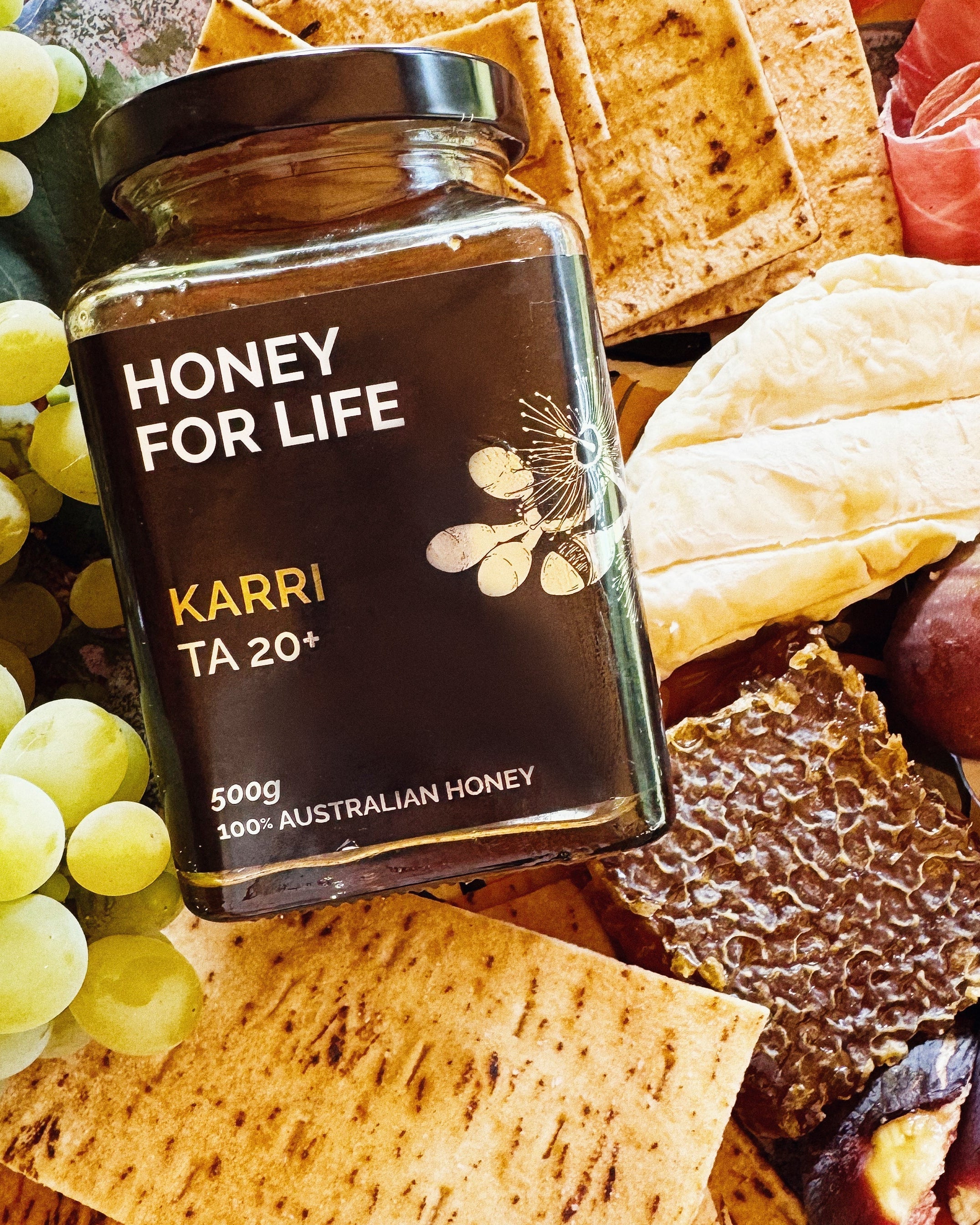 さまざまな料理が並ぶテーブルに置かれた ACTIVE KARRI HONEY TA20+ の瓶で、蜂蜜の試食の場面を示している