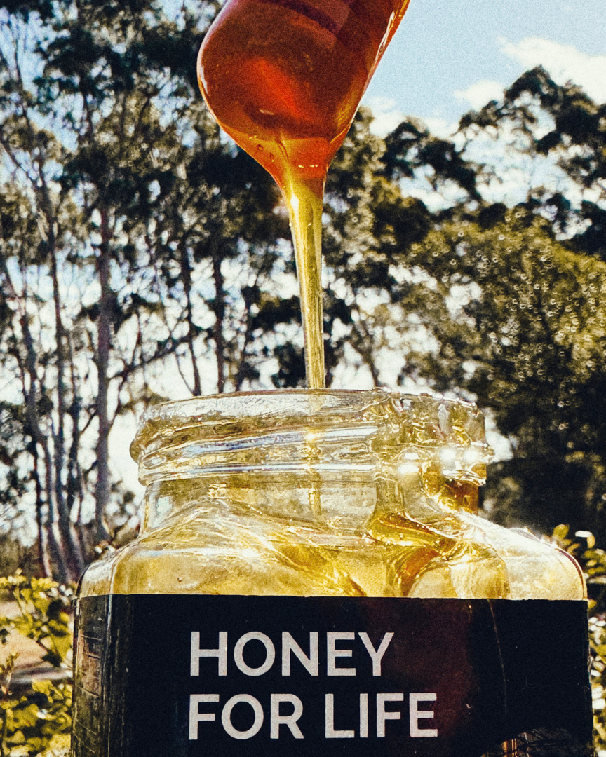 自然の屋外背景で「Honey for Life」とラベルされた瓶に蜂蜜が注がれている